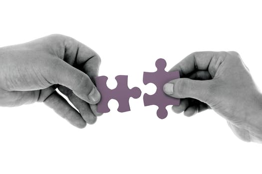 Two hands holding jigsaw pieces that fit together